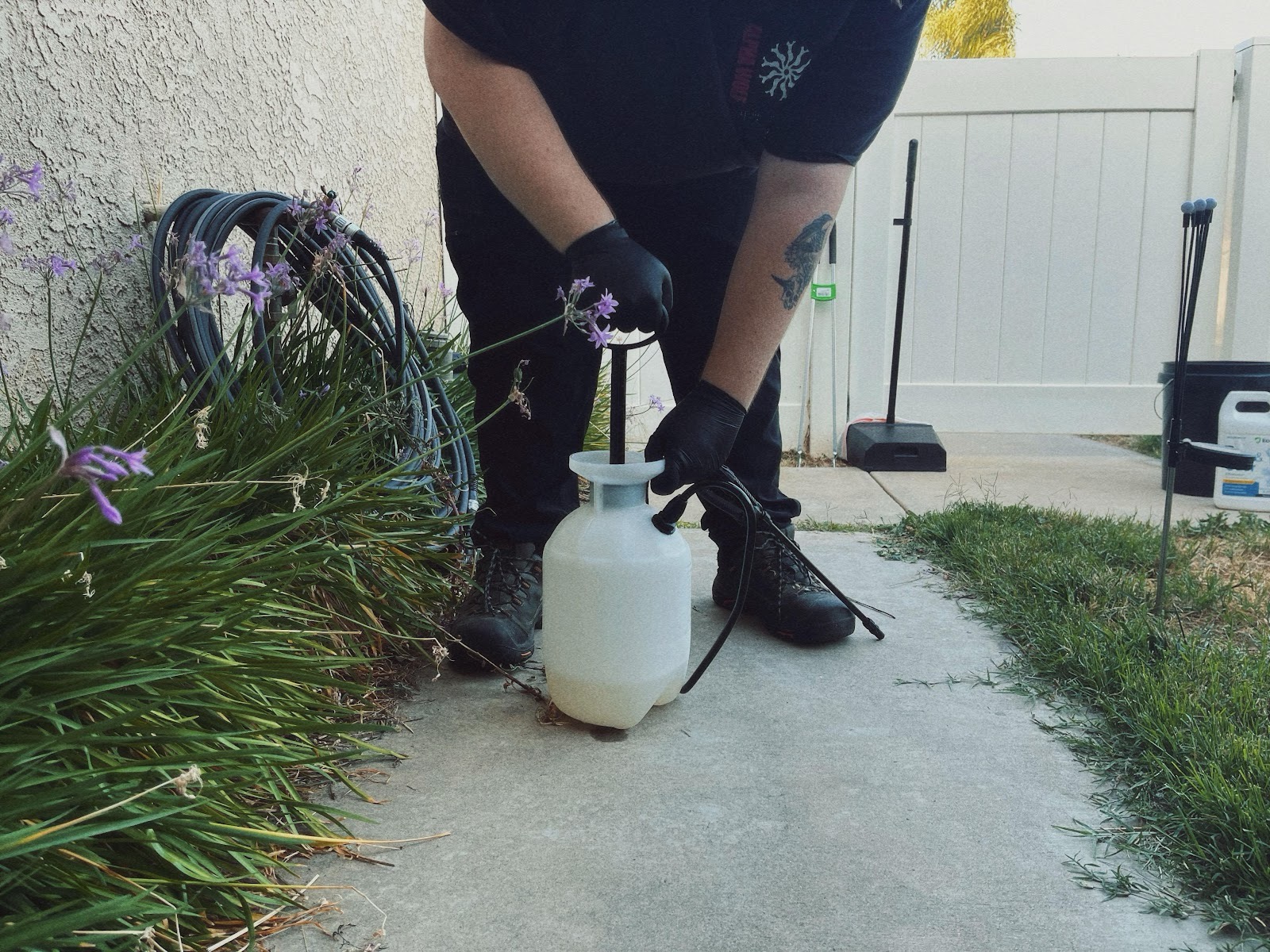 Stink Butts owner-operator with a pump sprayer in a customer backyard